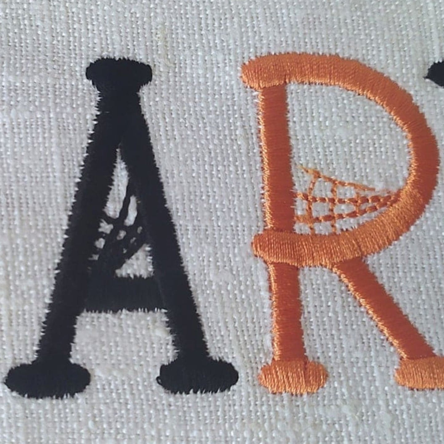 Embroidered letters 'A' and 'R' on a fabric background