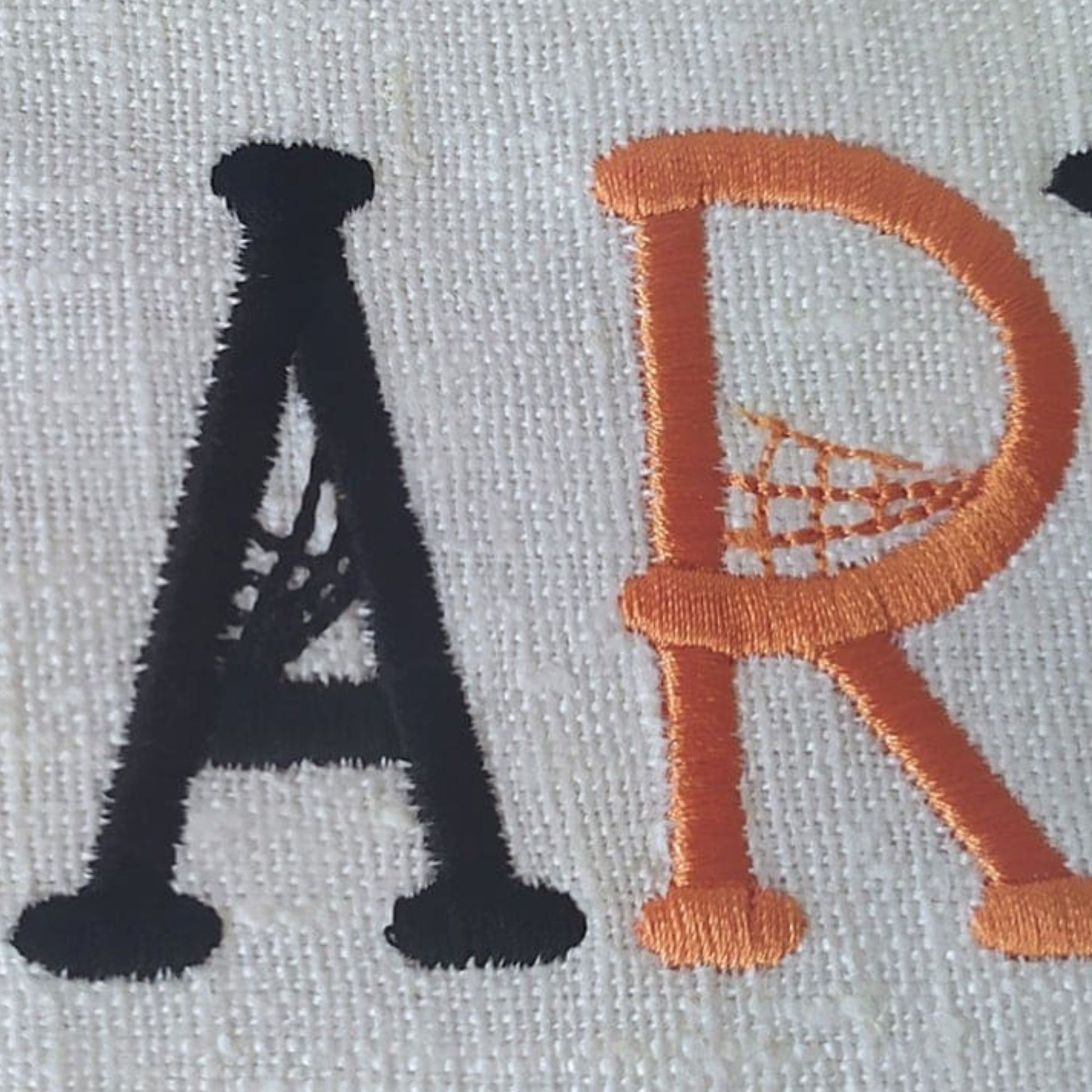 Embroidered letters 'A' and 'R' on a fabric background