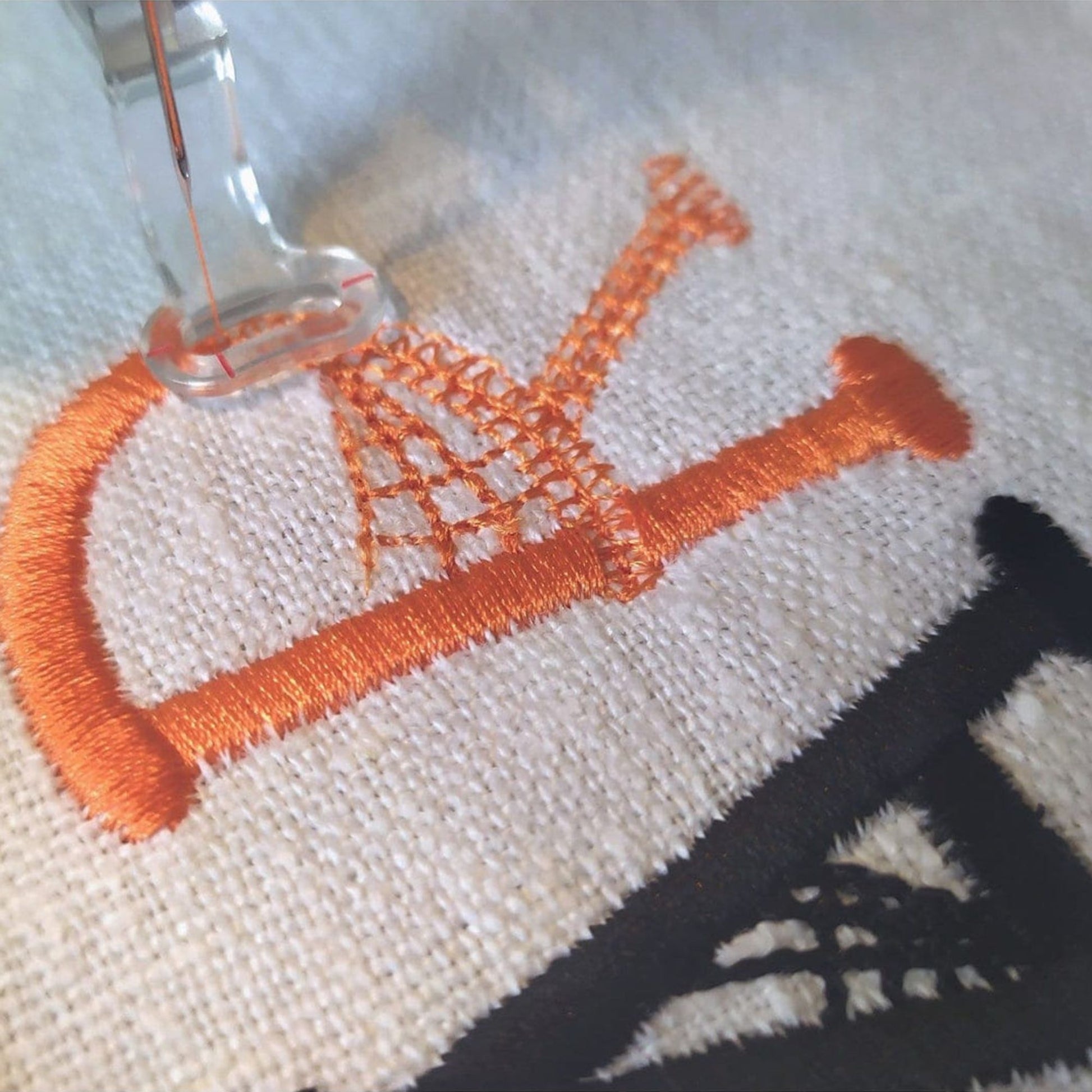 Embroidery hoop with orange thread on a white fabric background